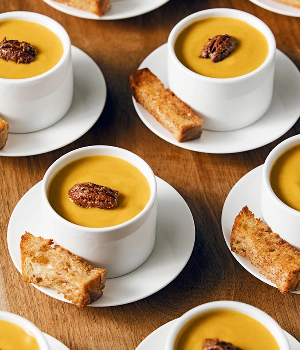 "little cups filled with butternut squash soup with caramelized pecan and toast"