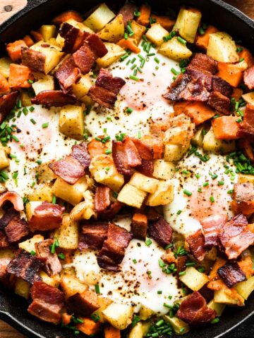 Close up of breakfast skillet with eggs, bacon, and potatoes.
