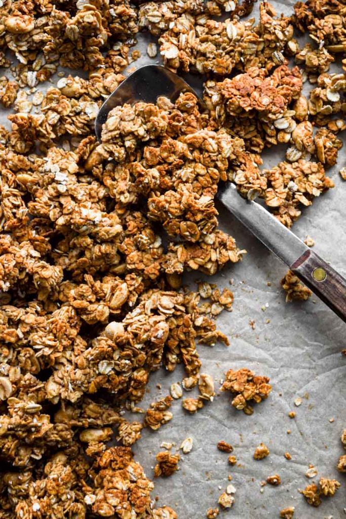 Granola broken apart on a sheet tray with spoon