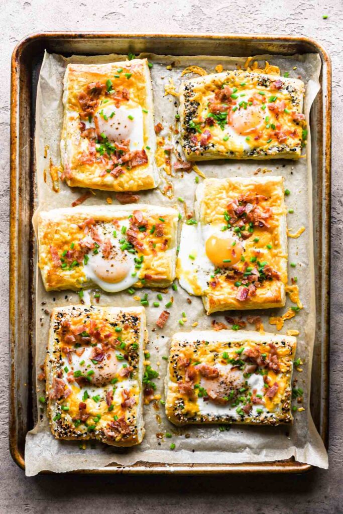 Finished puff pastry breakfast egg tarts topped with bacon and chives.