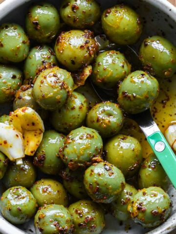 Close up photo of marinated olives in a serving bowl.