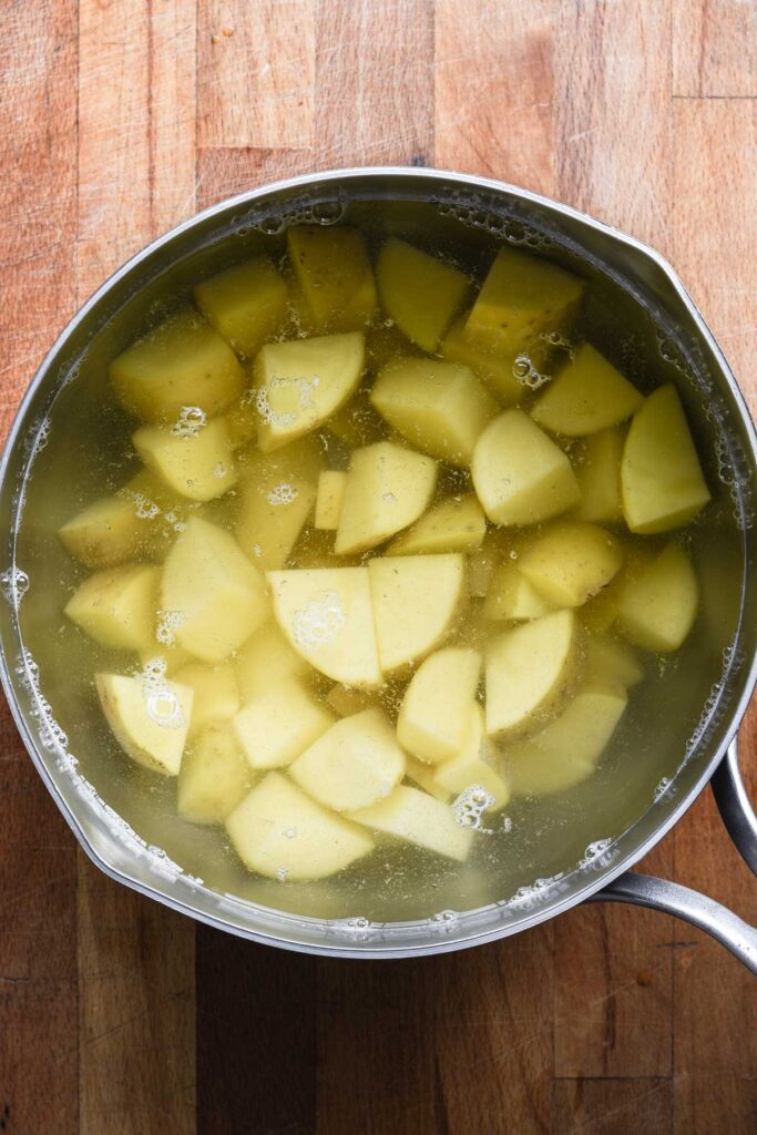 Boiling potatoes until fork tender.
