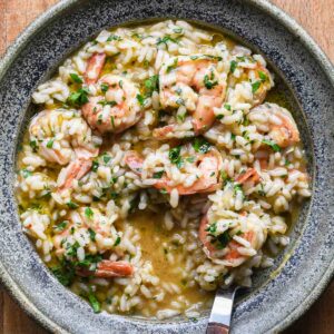 Shrimp scampi risotto in a blue bowl with a wood fork.