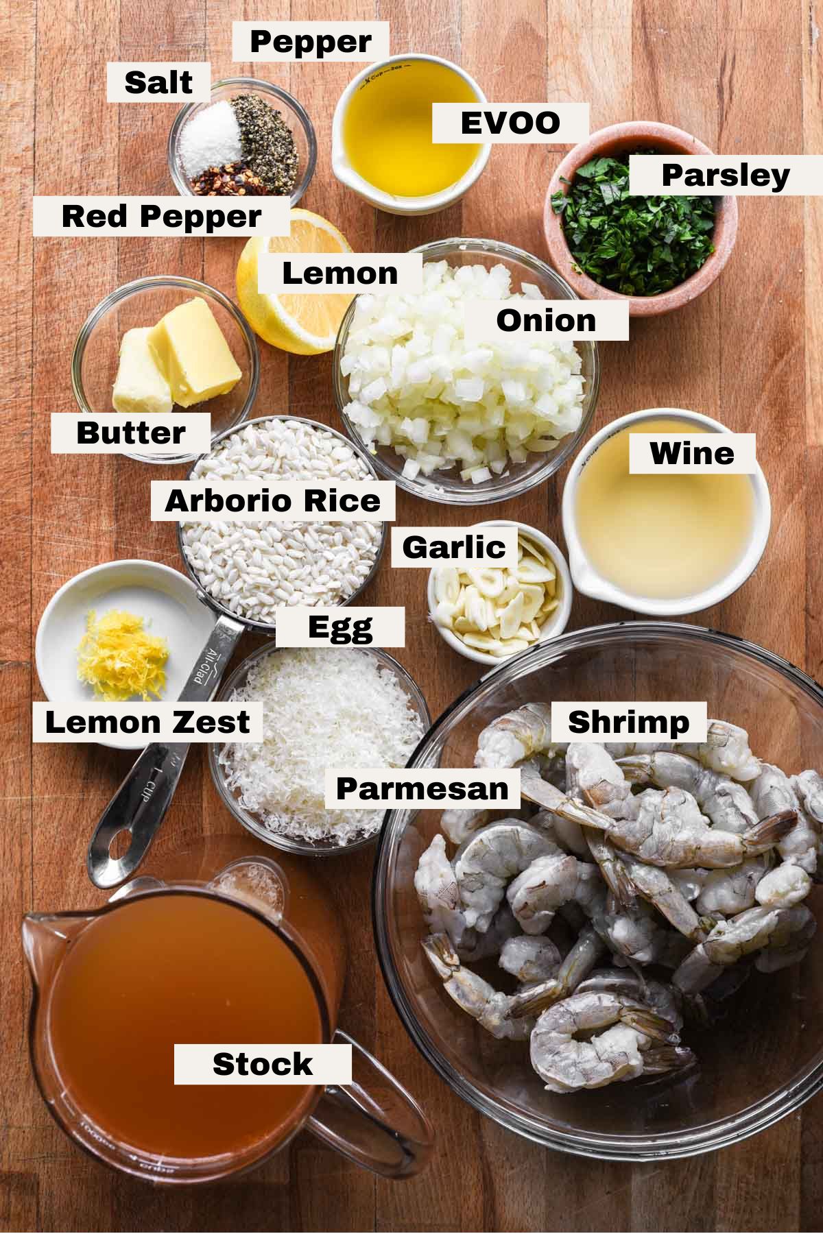 Ingredients needed to make shrimp scampi risotto labeled on a table.