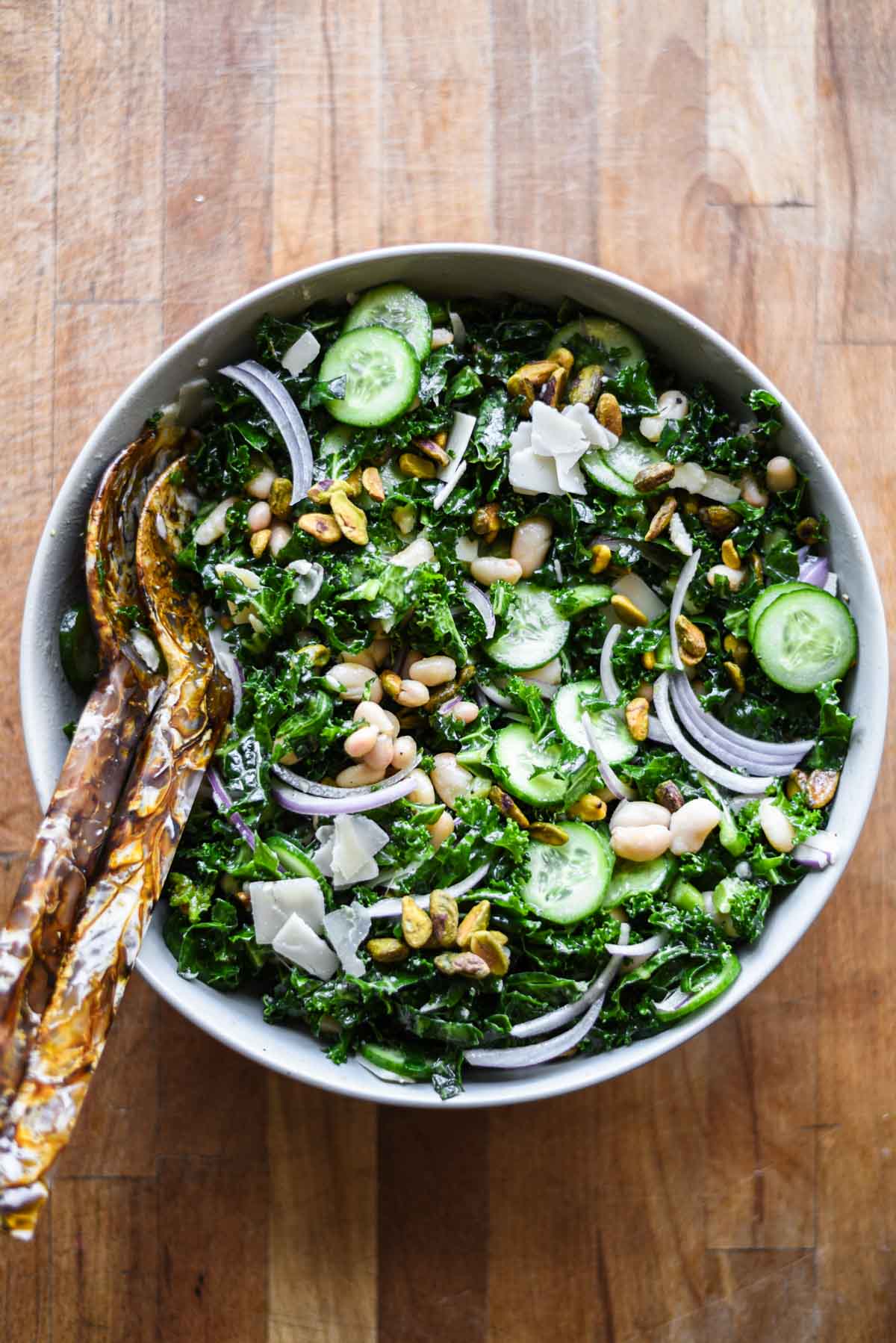 Kale and White Bean Salad in a bowl with serving utensils.
