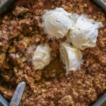 Pumpkin crisp with a spoon and melting ice cream.
