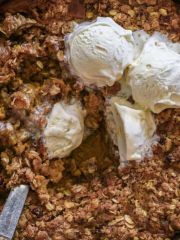 Pumpkin crisp with a spoon and melting ice cream.